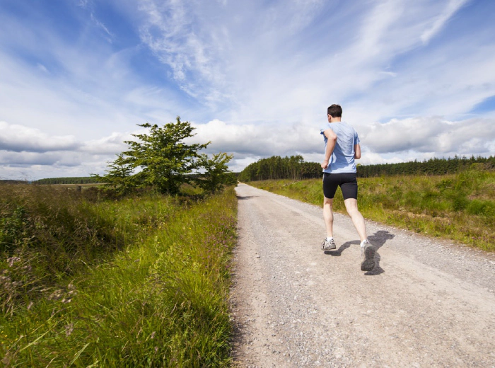 Runner moving barefoot on a natural trail at sunrise