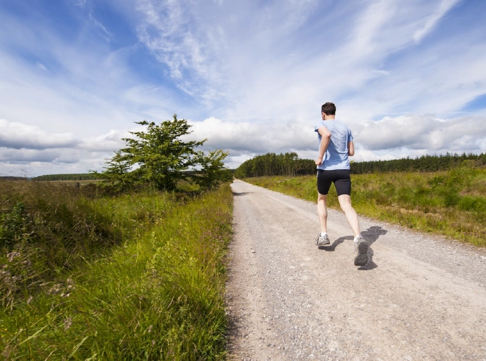 Runner moving barefoot on a natural trail at sunrise