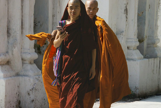 Buddhist monks walking barefoot near a white temple
