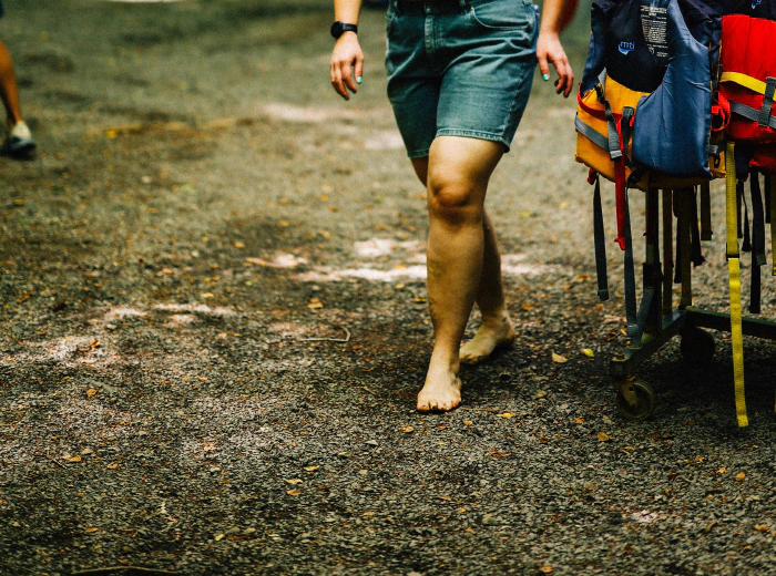 Woman walking barefoot through a forest, smiling, fully present
