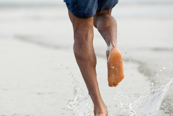 Person running barefoot on natural terrain showing proper form