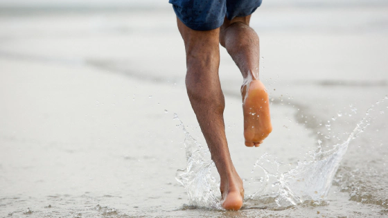 Person running barefoot on natural terrain showing proper form