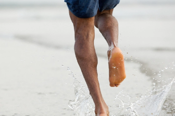 Person running barefoot on natural terrain showing proper form