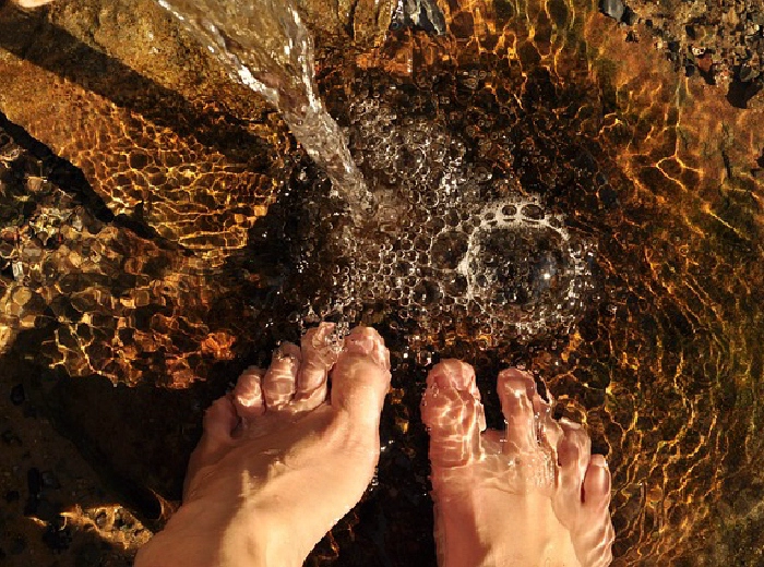 Bare feet standing in a golden sunlit stream
